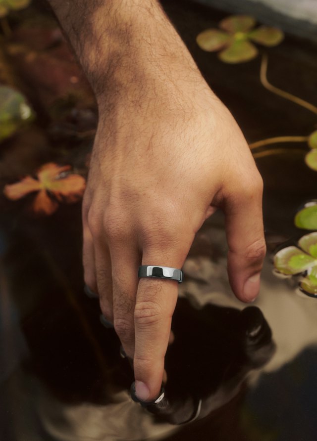 A hand wearing a Silver Oura Ring 5 at the surface of a pond